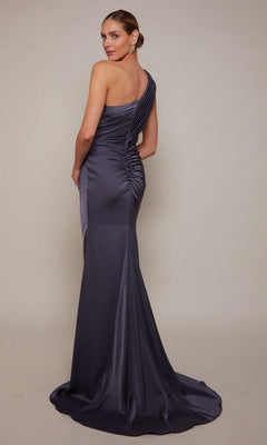 A woman stands looking over her shoulder in the Alyce 27697, a long formal dark purple one-shoulder satin evening gown with ruching detail—perfect for prom.