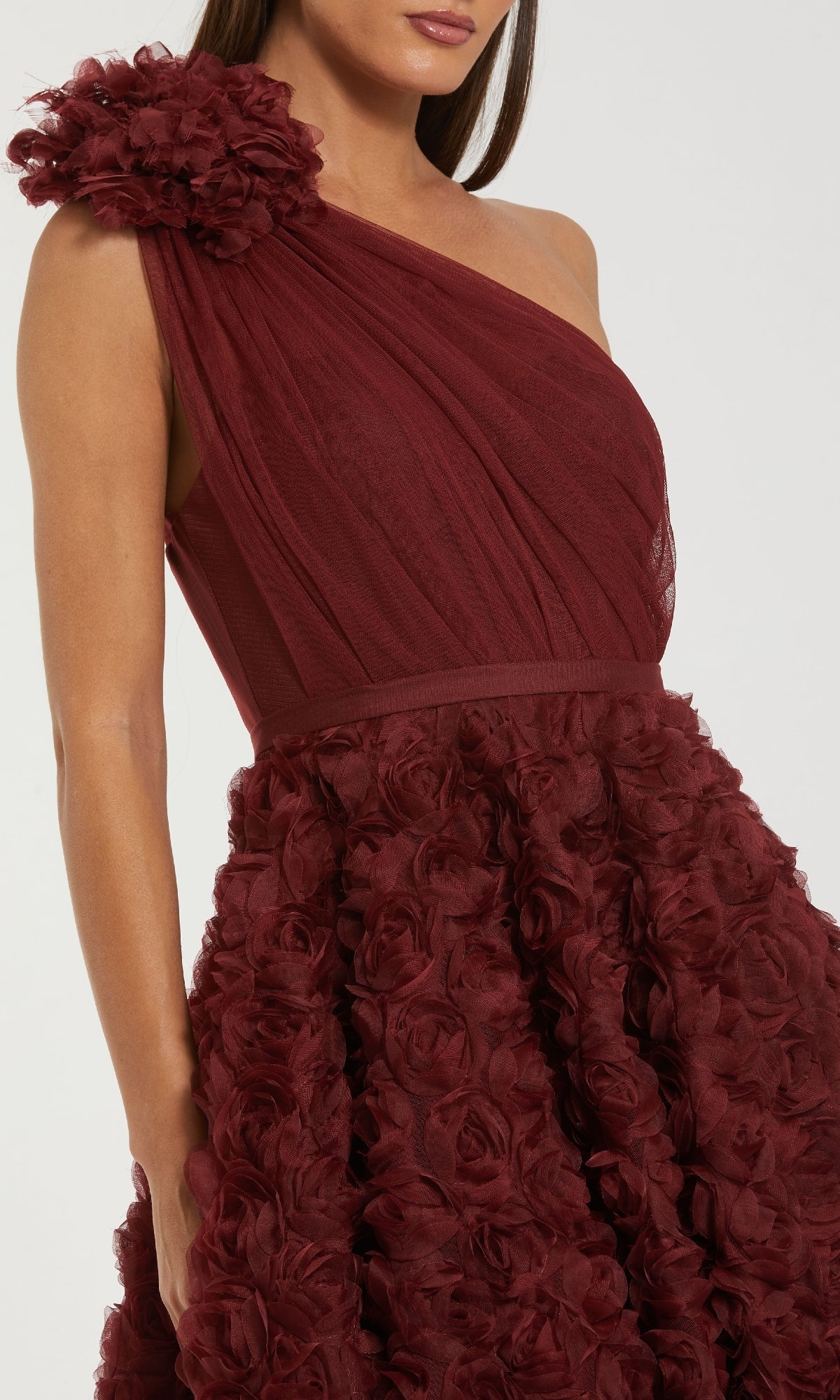 A woman wears the Mac Duggal 27698 Midi Wine Wedding Guest Dress, a one-shoulder design with a floral applique strap and textured rose details for a romantic look.