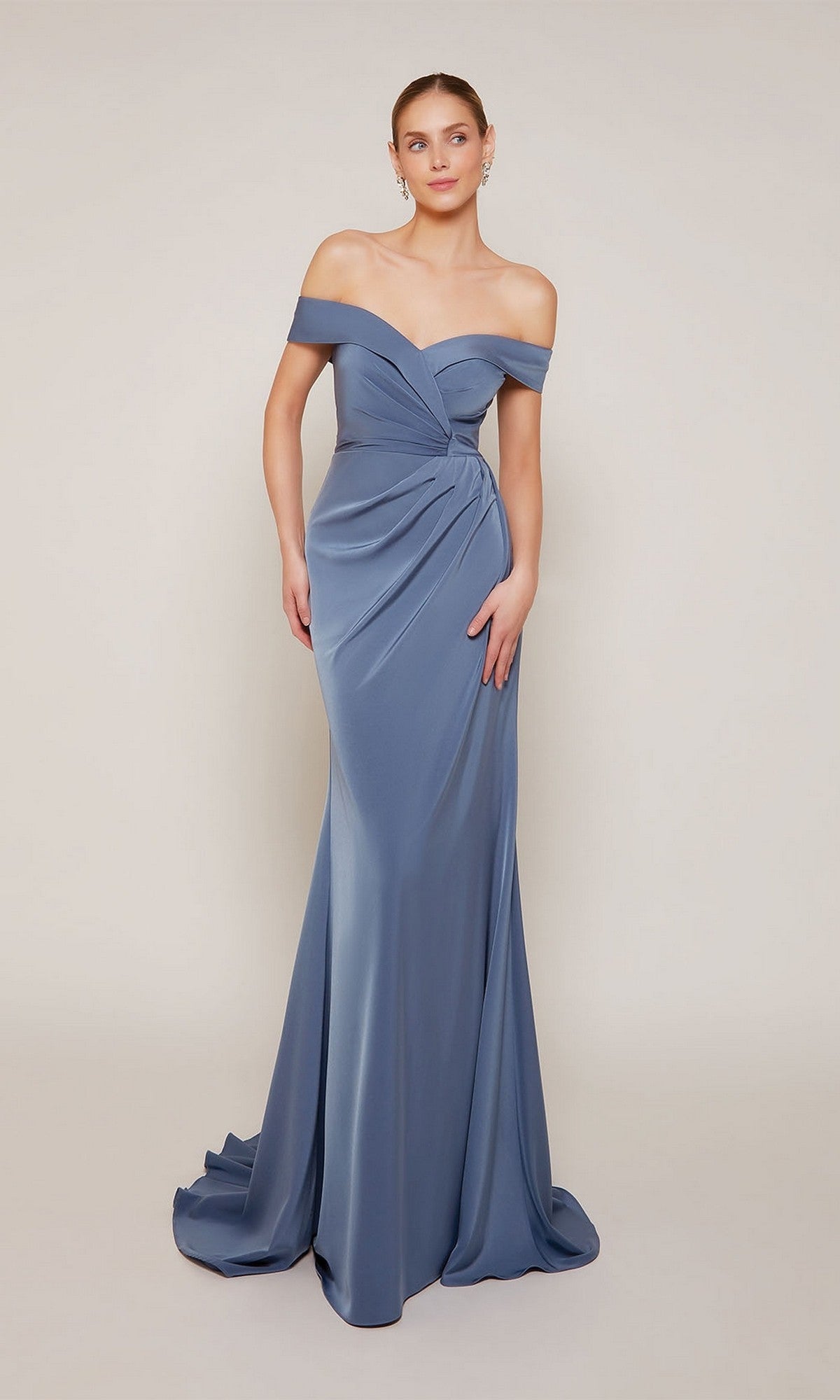 A woman models the Alyce 27698, a dark French blue, off-the-shoulder long formal dress with draped details and a slight train, standing against a simple light background.