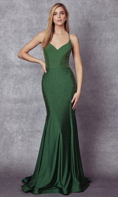 A woman in the Stone-Embellished Long Formal Prom Dress 276—a fitted, floor-length green gown with thin straps and subtle embellishments—stands against a textured gray background.