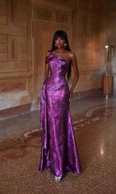 A woman in the Alyce 27701 long formal dress stands on a patterned floor in an ornately decorated room with warm-toned walls.