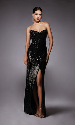 A woman wearing the Alyce 27704 long black formal dress, featuring a strapless sequin design and thigh-high slit, paired with silver earrings and strappy heels, stands against a plain gray background.