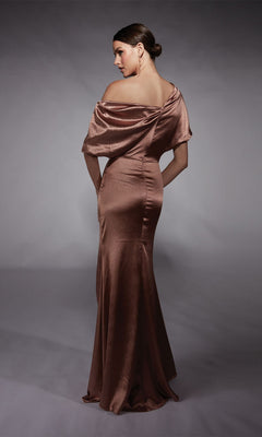 A woman wears the Long Formal Dress: Alyce 27721, a satiny, off-the-shoulder gown, as she faces away and glances over her shoulder against a plain gray background.