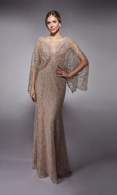 A woman models the Alyce 27724 long formal dress, a light brown lace gown with sheer cape-like sleeves and crystal beaded embellishments, standing against a plain gray background.