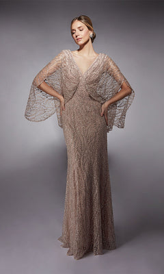 A woman stands with hands on hips against a plain gray background, wearing the Alyce 27724 long formal dress in sultry blush, featuring sheer beaded cape sleeves and crystal embellishments.