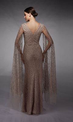 A woman in the Alyce 27725 long formal dress—an embellished floor-length sheath with sheer, beaded cape sleeves—stands with her back to a gray background.