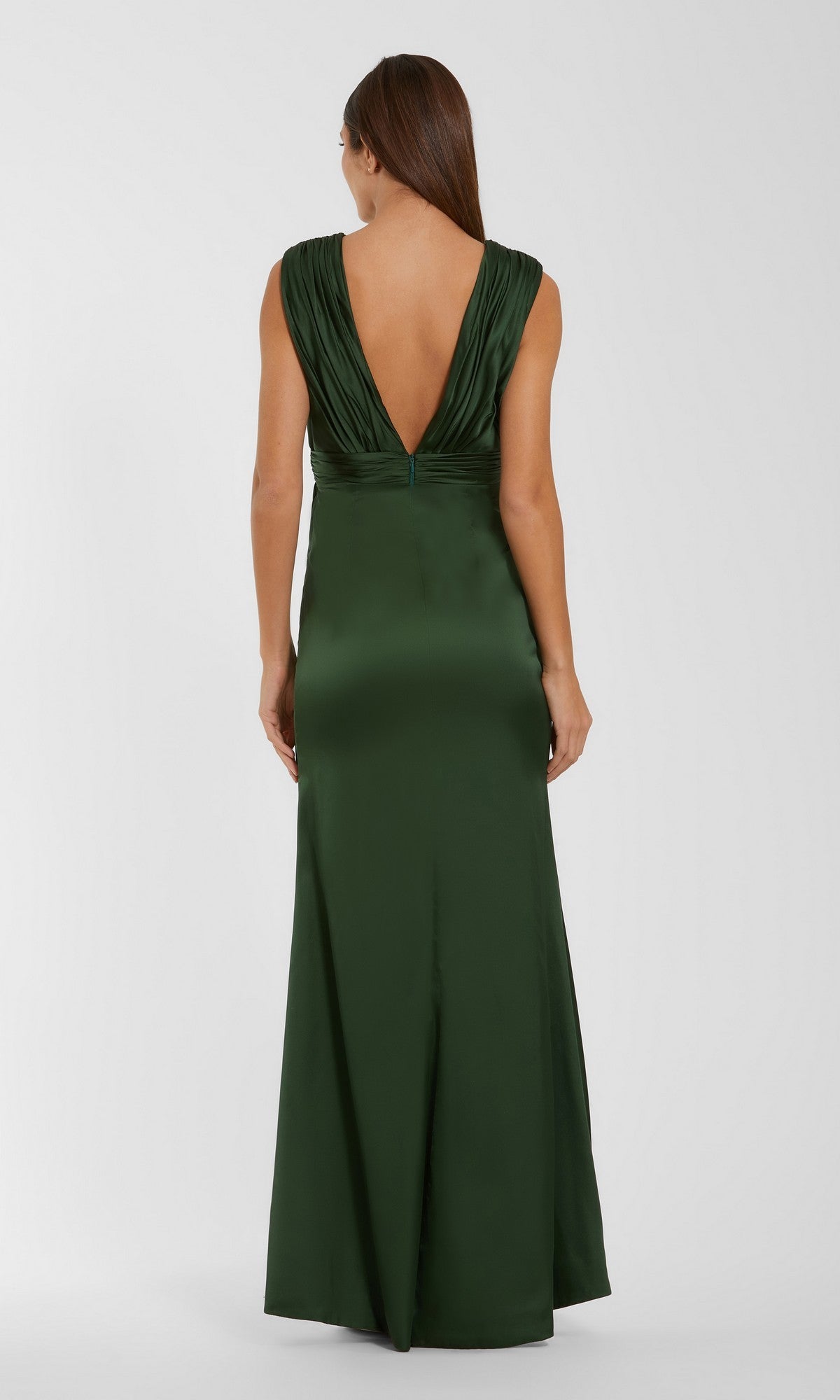 A woman stands with her back to the camera against a plain, light background, modeling the Long Formal Dress: Mac Duggal 27728—an elegant, olive green gown with a deep V-back. The sleeveless design is elevated by intricate 3D floral applique detailing, adding texture and sophistication to the overall silhouette.