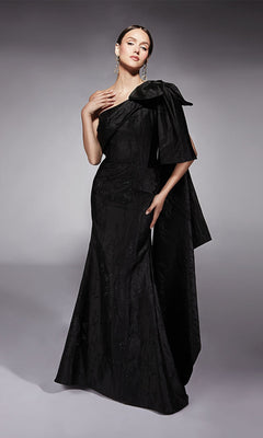 A woman poses in the Alyce 27731 long formal dress, featuring a one-shoulder design with an oversized bow detail, against a plain gray background.