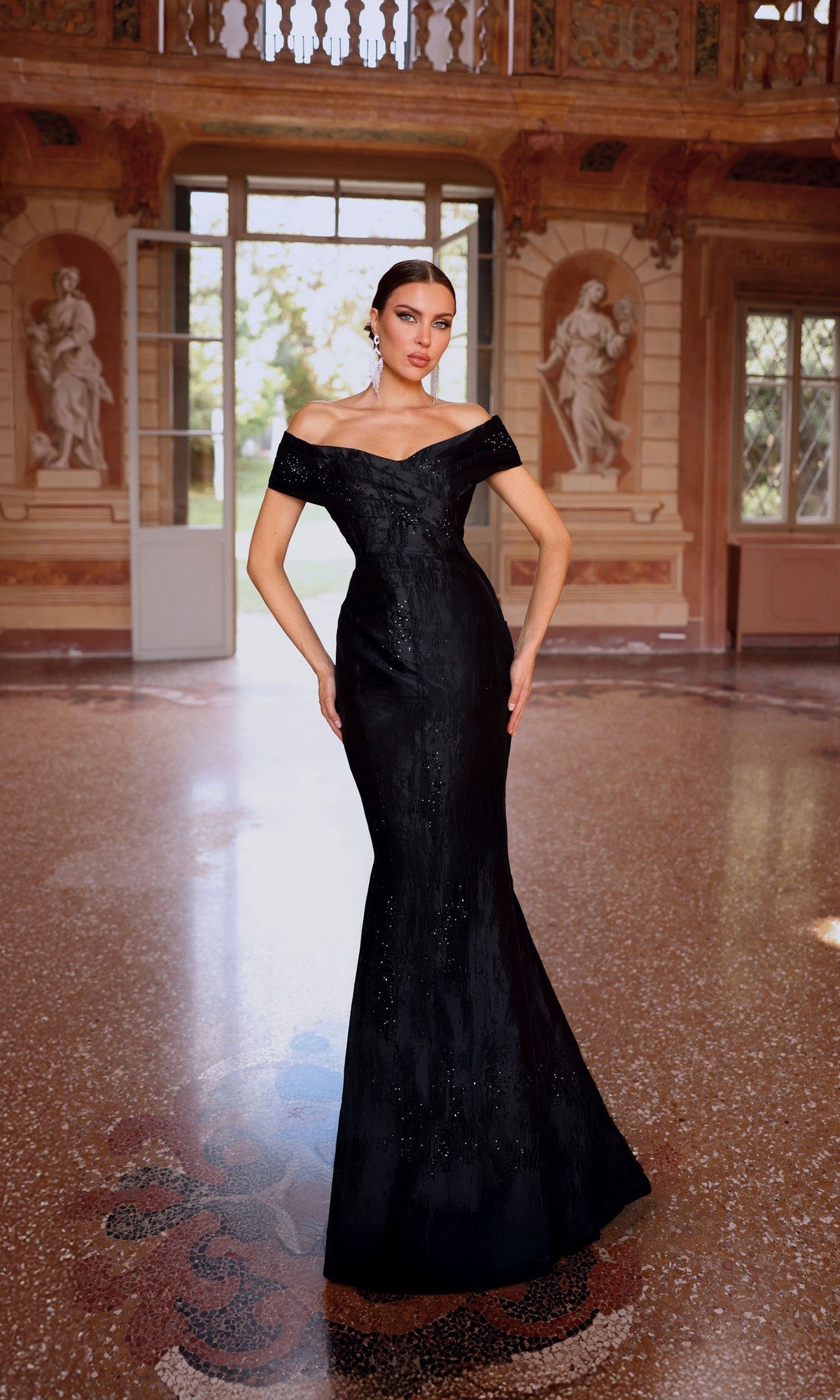 A woman stands in an ornate room with statues, wearing the Alyce 27733 long formal dress in a jacquard mermaid silhouette—an elegant choice for sophisticated evening events.