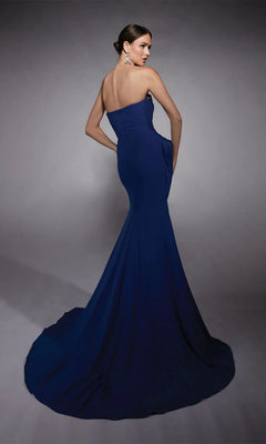 A woman models the Alyce 27739 Long Formal Dress, a strapless navy gown with a sweetheart neckline and long train, standing against a gray background and looking elegantly over her shoulder.