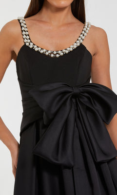 Black dress with pearl embellishments on a plain background