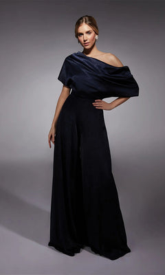 A woman poses in a studio wearing the Alyce 27743 Long Formal Jumpsuit in Midnight with statement earrings, ideal for a mother-of-the-bride look, against a plain gray background.