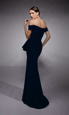 A woman wearing the Alyce 27744 long formal dress stands with her back turned, glancing over her shoulder against a plain studio backdrop.