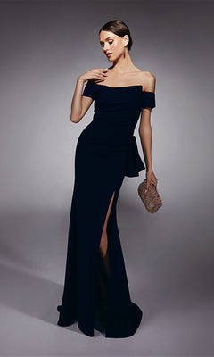 A woman poses against a plain background wearing the Alyce 27744 long formal off-the-shoulder dress with a high-leg slit and holding a textured clutch bag.
