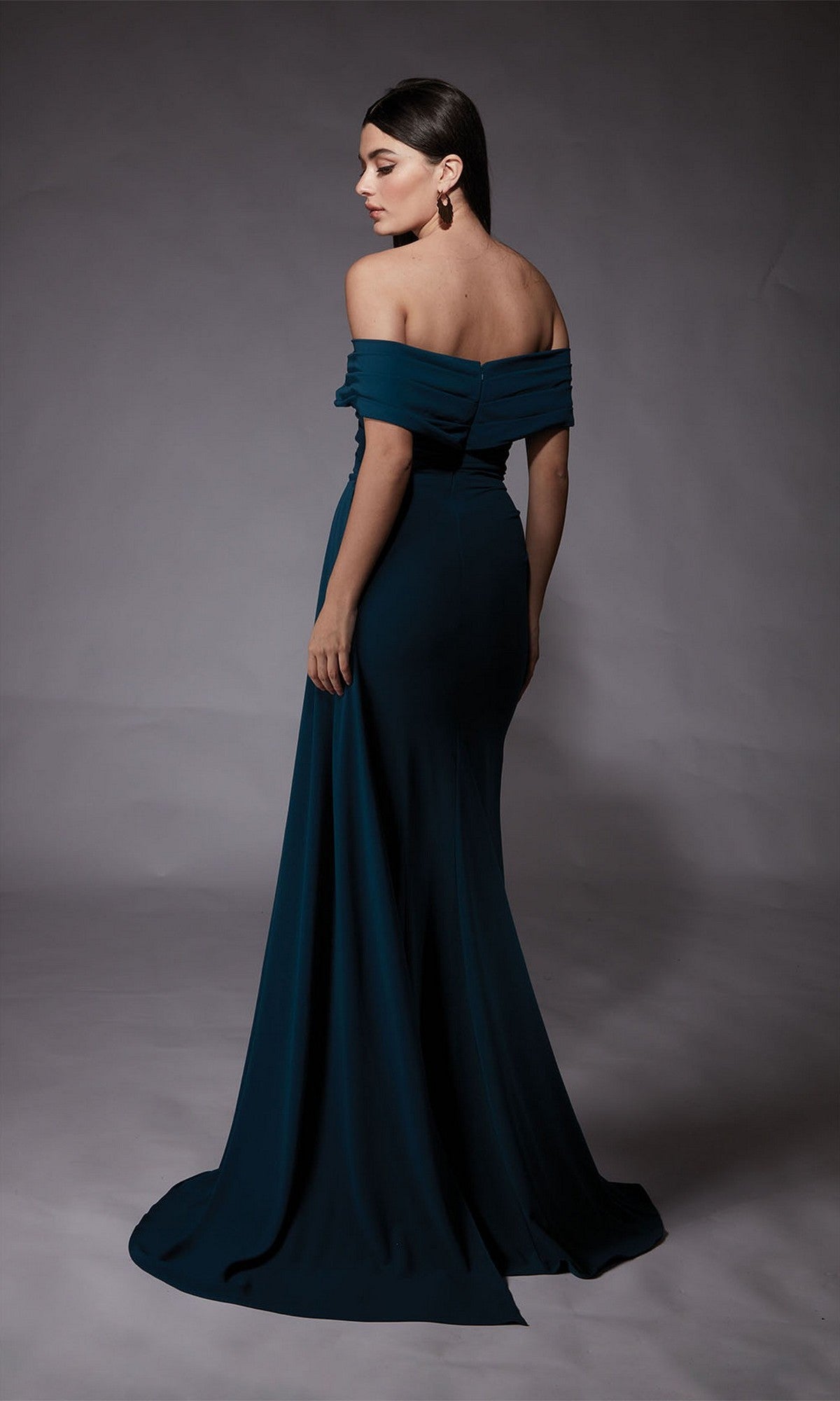 Woman in the Long Formal Dress: Alyce 27745 stands turned slightly away, posing against a plain gray backdrop—perfect for elegant prom style.