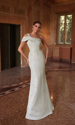 A woman in the Alyce 27749 Long Formal Dress, featuring a fitted sheath silhouette and cold-shoulder sleeves, stands in an elegant room with ornate walls and tall windows.
