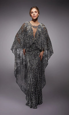 A woman wears the Alyce 27752, a floor-length silver-sequined formal dress with sheer cape-like sleeves, standing against a plain gray background.