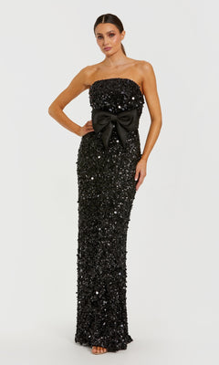 Black sequin strapless gown with a large bow on a white background