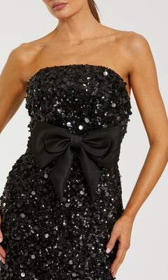 Black sequin strapless dress with a large bow on a white background