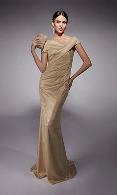 A woman models the Alyce 27762 long formal dress in gold, featuring an off-the-shoulder glitter jersey design. She poses against a neutral background with a matching clutch and long drop earrings.