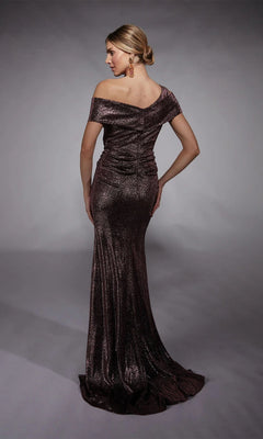 A woman with her hair in a low bun stands facing away, showcasing the back of the Alyce 27762 long formal dress—an off-the-shoulder, dark glitter jersey gown.