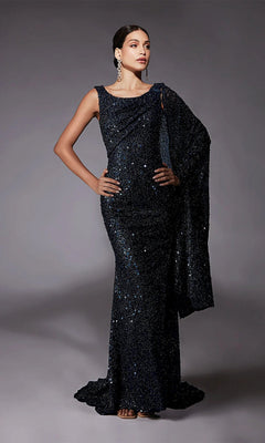 A woman poses in the Alyce 27772 long formal dress in midnight, featuring sequin beading and a matching draped shawl, set against a plain gray background.