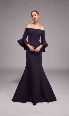 A woman models the Alyce 27777 long formal dress in navy, featuring an off-the-shoulder mermaid design with flared sleeves, against a plain gray background.