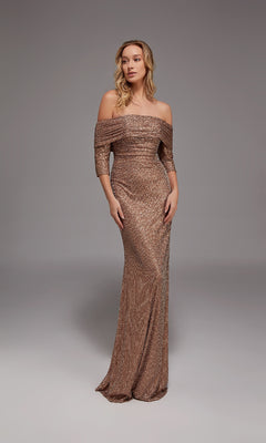 A woman stands gracefully in the Alyce 27787 long formal dress in latte—an off-the-shoulder gown with three-quarter sleeves, creating an elegant mother-of-the-bride look against a plain gray background.
