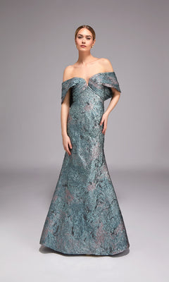 A woman models the Alyce 27794 long formal dress, an off-the-shoulder, floor-length jacquard gown in textured blue, set against a plain grey background—ideal for special events.