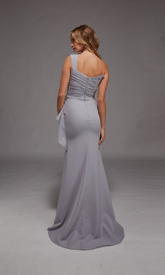 A woman stands facing away, wearing the Alyce 27812 long formal dress in light lavender, featuring a fitted waist, one-shoulder neckline, and elegant draped fabric detail.