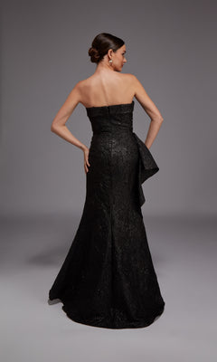 A woman in the Alyce 27818 Long Formal Dress, featuring a strapless jacquard design with a fitted bodice and flared skirt, stands facing away with hand on hip against a plain gray background—elegance from every angle.