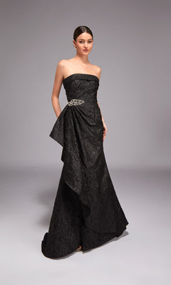 A woman models the Alyce 27818 long formal dress, a strapless jacquard gown with a decorative belt, standing elegantly against a simple gray background—ideal for special occasions.
