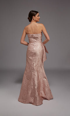 A woman models the Alyce 27818, a strapless jacquard long formal dress in rose gold, standing with her back to the camera against a plain gray background—the perfect choice for any special occasion.