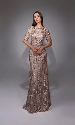 A woman stands wearing the Alyce 27819 long formal dress, a floor-length light mauve gown with sequin and floral embroidery, illusion neckline, sheer short sleeves, and a fitted embellished bodice.