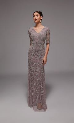 A woman wears the Alyce 27824 long formal dress in Lilac Grey/Silver, featuring beaded embroidery and elegant details, standing against a plain gray background—ideal for formal occasions.