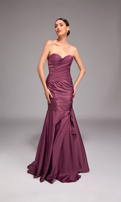 A woman poses against a gray background in the Alyce 27836, a strapless long formal dress with a sweetheart neckline, fitted mermaid skirt, ruched detailing, and slight flare at the hem in purple.