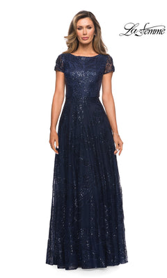 A woman wearing a navy, floor-length La Femme 27837 formal dress with short lace sleeves and an embroidered, sequined overlay.