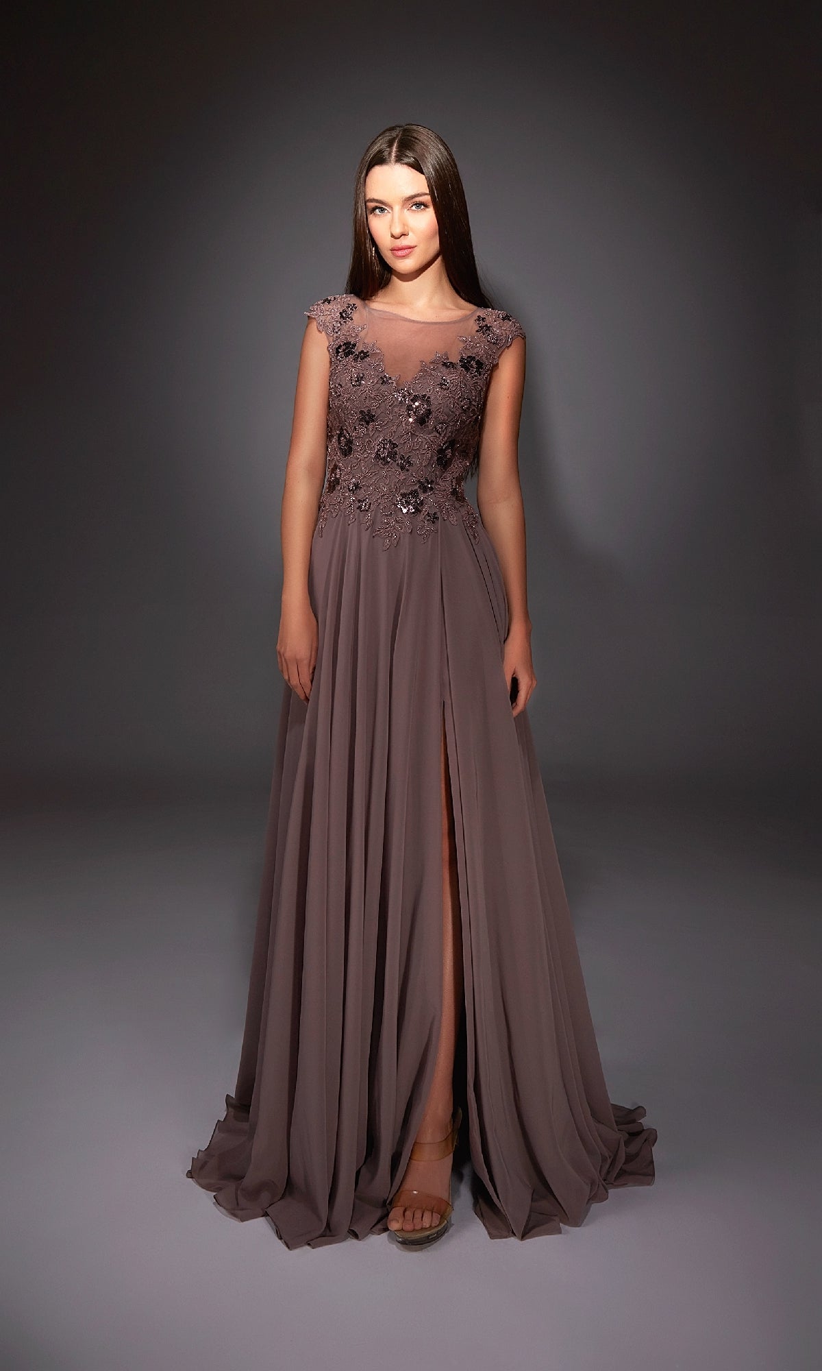 A woman poses gracefully in the Alyce 27842 long formal dress—mauve chiffon, A-line silhouette, floral embellished bodice, and a high skirt slit—set against a dark background.