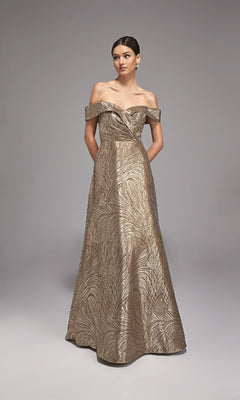 A woman poses against a plain background in the Alyce 27844 long formal dress, featuring metallic jacquard fabric, off-the-shoulder floor-length silhouette, and a delicate leaf pattern—an elegant choice for a mother-of-the-bride.