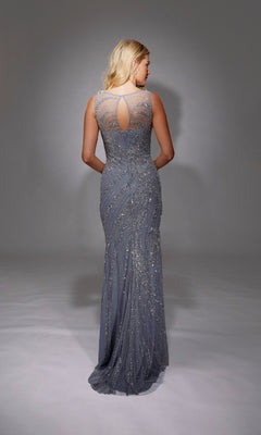 A woman faces away, wearing the Long Formal Dress: Alyce 27846—a floor-length silver-gray sheath with intricate beading and a sheer back panel featuring a keyhole detail.