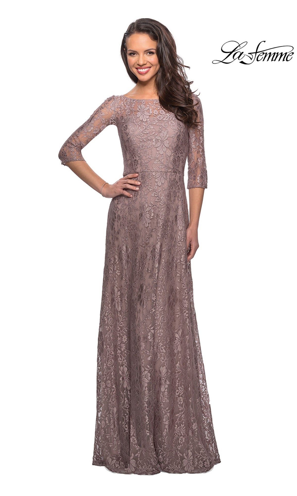 A woman wearing a cocoa-colored La Femme 27857 long formal dress featuring floor-length lace, three-quarter sleeves, and a high illusion neckline.