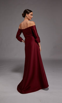 In a neutral studio, a woman in the Alyce 27859 long formal dress—floor-length, off-the-shoulder, and burgundy—stands with her back slightly turned; an elegant mother-of-the-bride option.