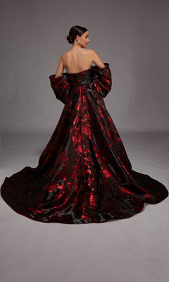 Woman wearing the Alyce 27862 long formal dress—a stunning strapless black floral jacquard gown with red patterns and a long train—stands with her back to the camera against a plain background.