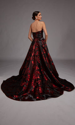 A woman faces away from the camera in the Alyce 27862, a strapless black floral jacquard gown with a red pattern, floor-length silhouette, and long train.