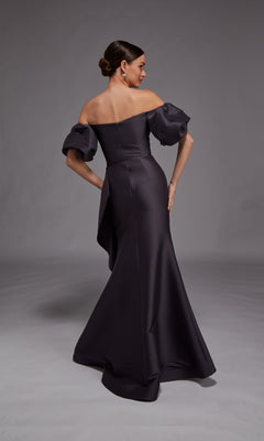 A woman stands facing away against a neutral backdrop, modeling the Alyce 27863 long formal dress—an off-the-shoulder design with puffed sleeves and a fitted silhouette.