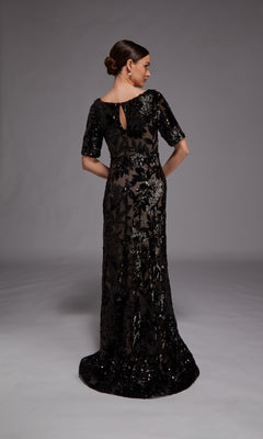 A woman faces away, wearing the Alyce 27876 Long Formal Dress with floral sequins and short sleeves—an elegant special occasion gown—set against a plain gray background.