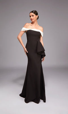 A woman models the Alyce 27877 long black formal dress, featuring an off-the-shoulder neckline with a white band and structured side detail, standing against a neutral backdrop.