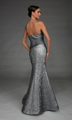 A woman stands facing away against a gray background, wearing the Alyce 27881 long formal dress—a strapless metallic silver mermaid evening gown with a fitted bodice and flared skirt.