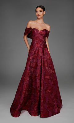 A woman poses against a plain gray background wearing the Alyce 27884, a long formal dress featuring an off-the-shoulder neckline, elegant jacquard fabric, and an A-line skirt.