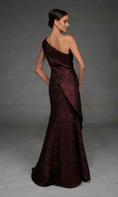 A woman stands facing away against a plain gray background, wearing the Long Formal Dress: Alyce 27885—a dark, shimmery, one-shoulder evening gown crafted from elegant metallic jacquard fabric that catches the light with every subtle movement.